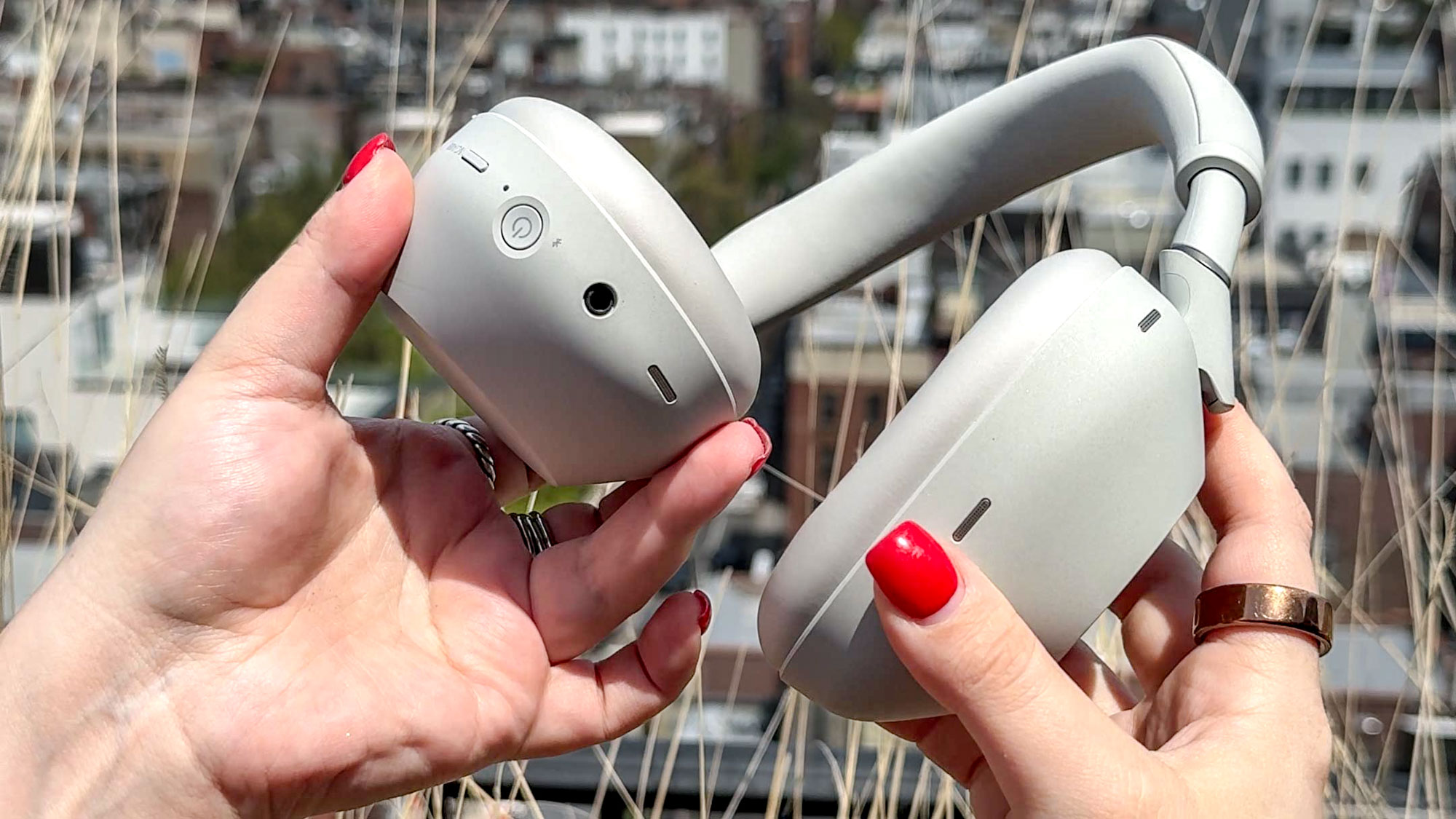 White Sony WH-1000XM6 noise-cancelling headphones showing the power and control buttons and the headphone jack port