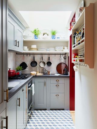 a small kitchen idea with grey/light blue cabinets, open shelving, black countertop and pots hanging by Neptune