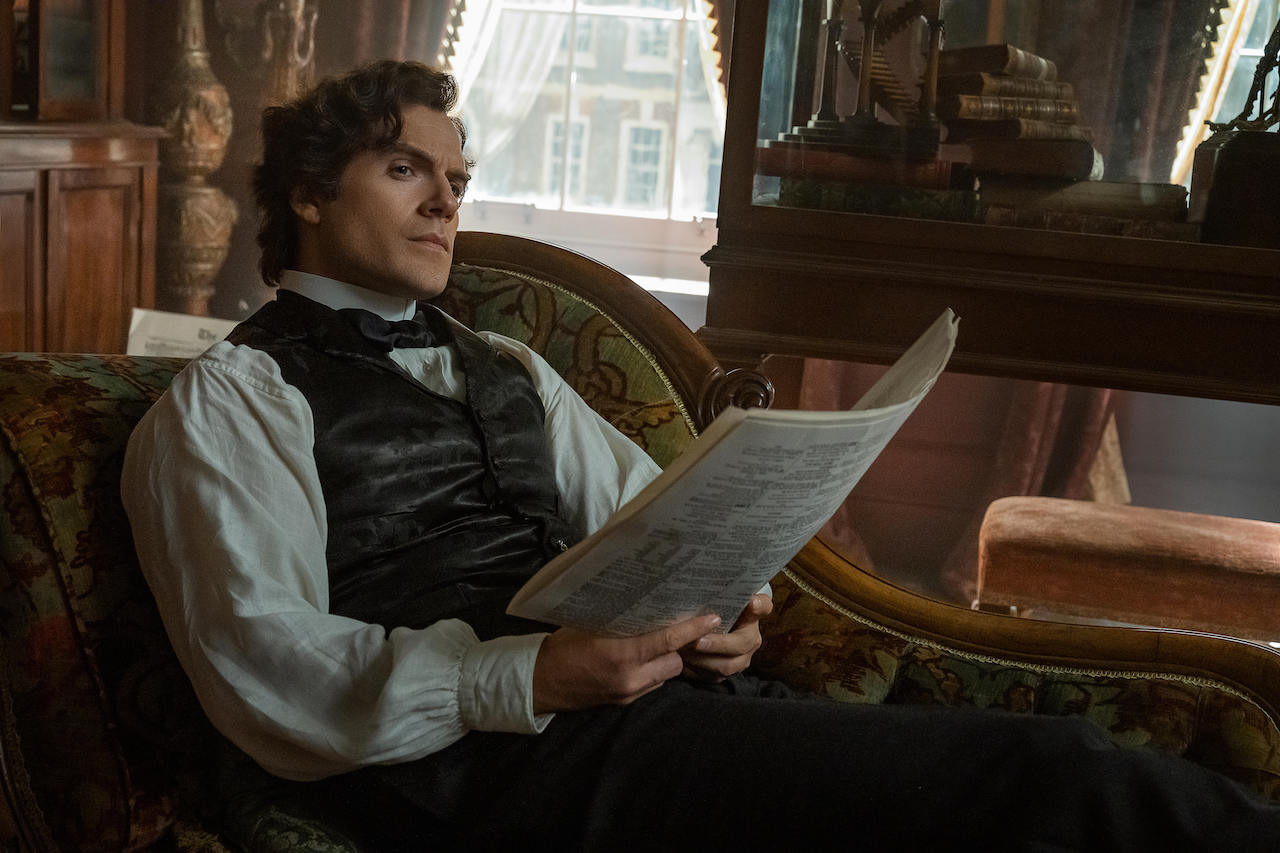 Sherlock Holmes de Henry Cavill mirando hacia arriba después de leer el periódico en Enola Holmes 2