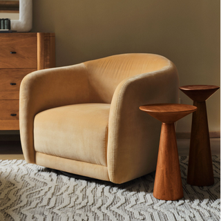 tan swivel arm chair paired with two wooden side tables over a textured rug