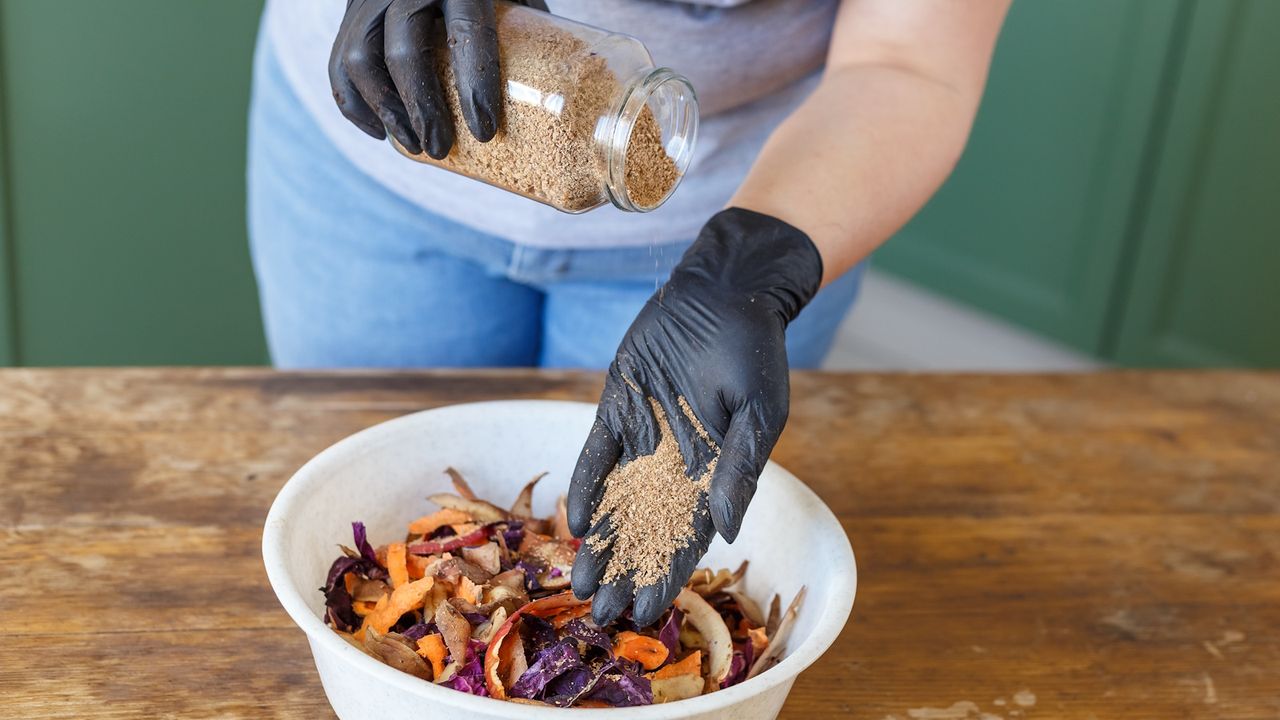 Woman puts bokashi into the pile of kitchen fruits and vegetable scraps for compost recycling