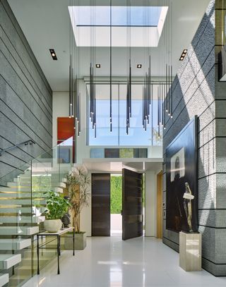 A large entryway with high ceilings, a chandelier lighting and floating staircase