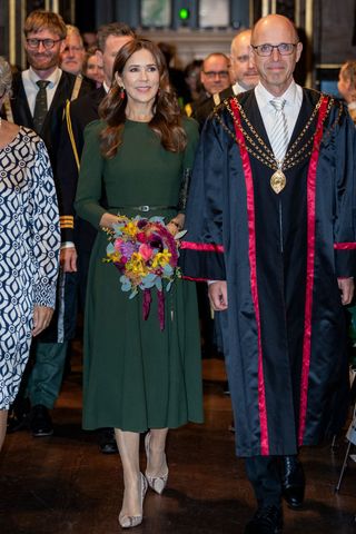 Queen Mary of Denmark wears a forest green midi dress with snakeskin heels and red earrings