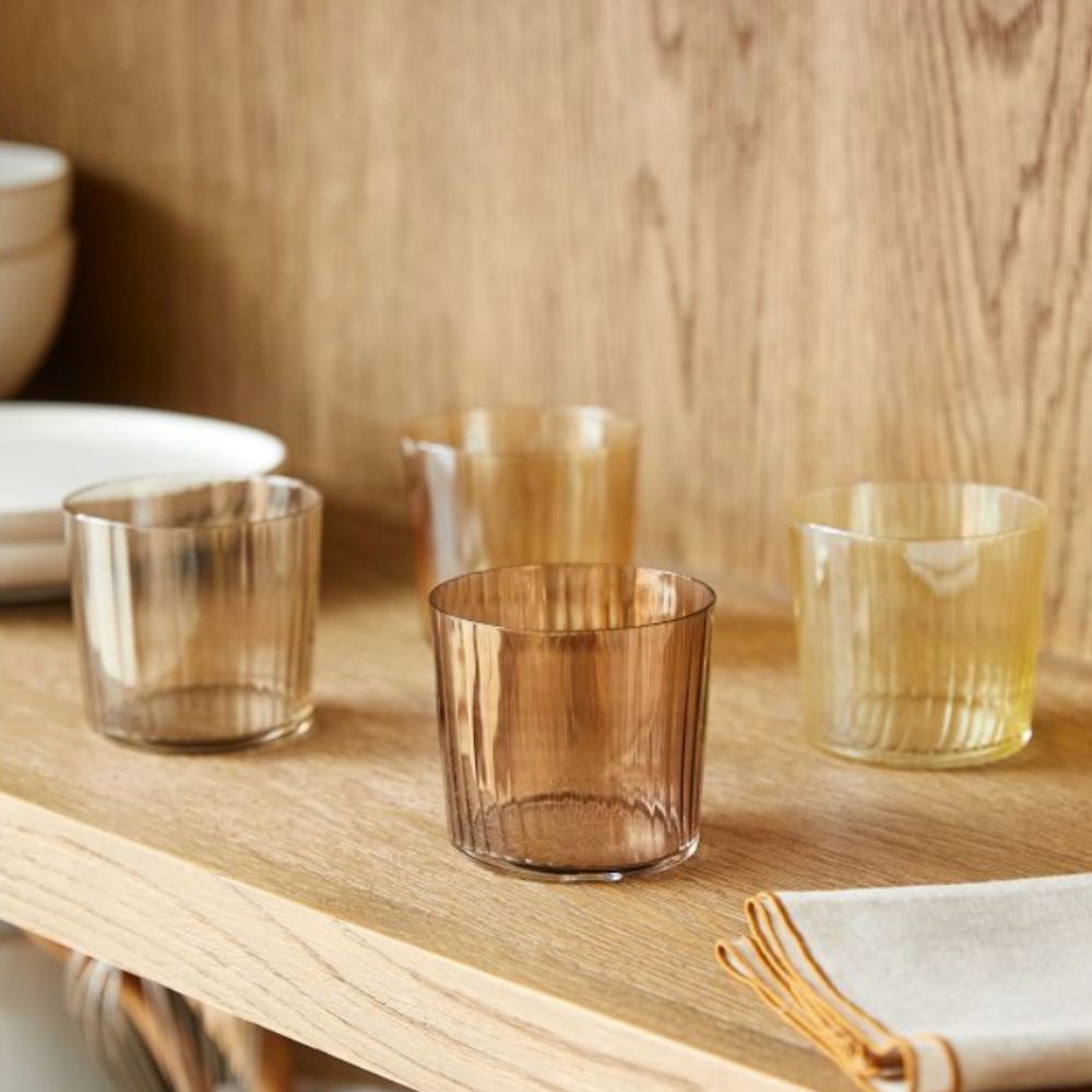 four colored glasses in varied shades of yellow and brown on a shelf