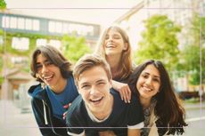 A group of teenagers outside, smiling