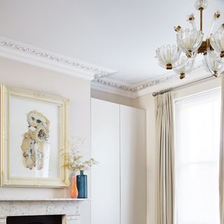 White living room with vintage chandelier and artwork above fireplace