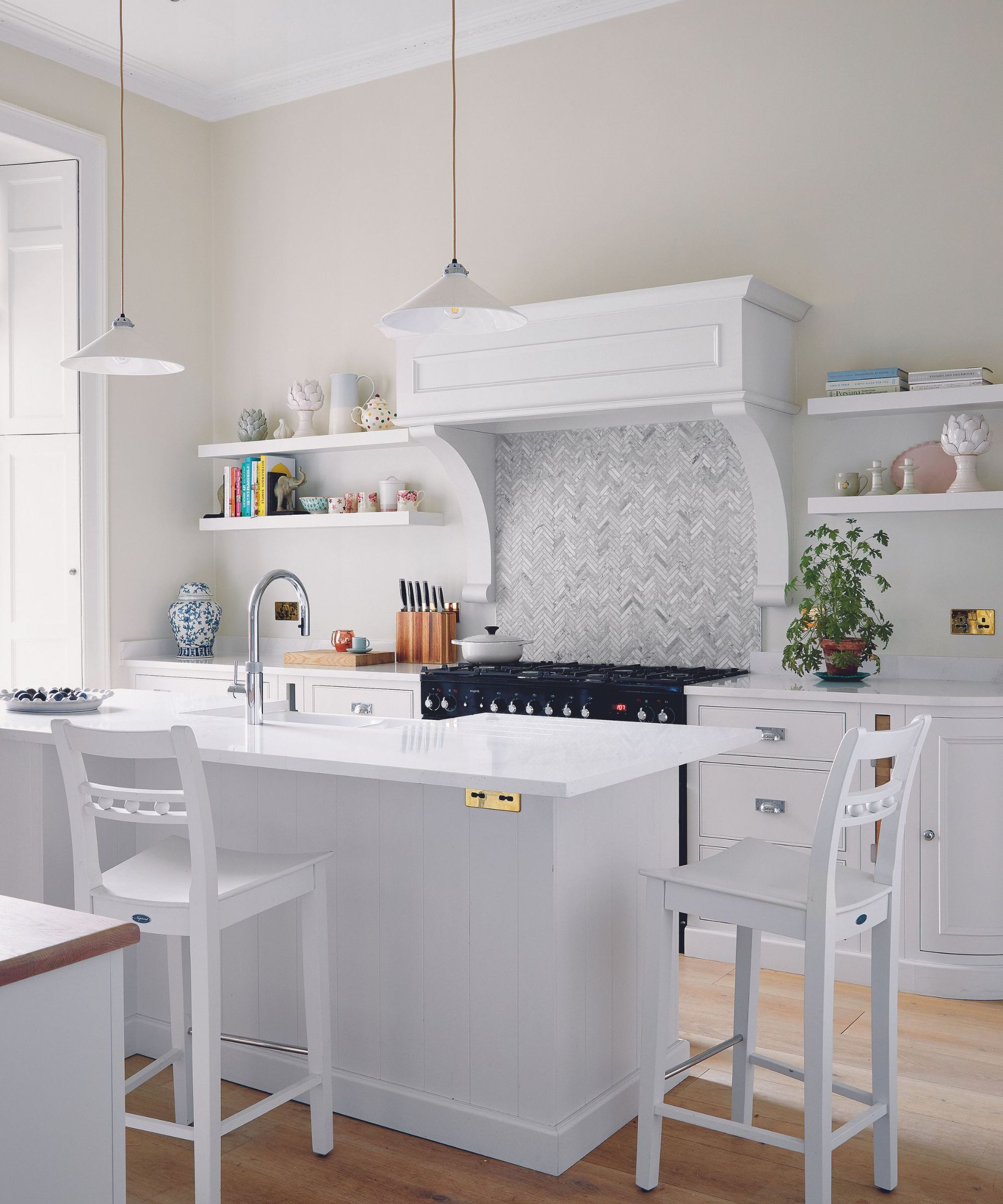 A white kitchen with a large range hood and shelving