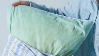 A person taking blue stained pillow with yellow patched out from a printed pillow case