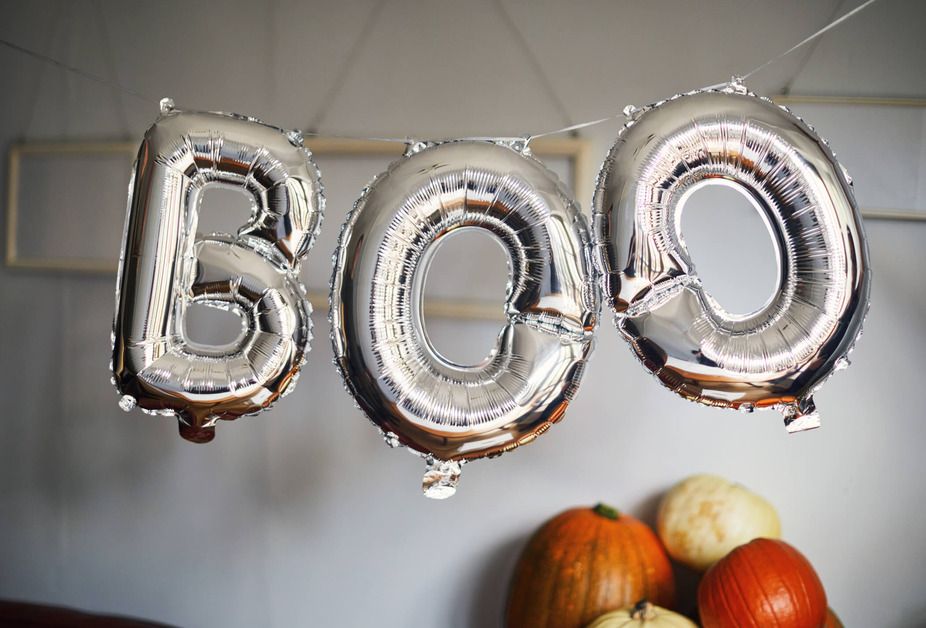 Silver balloons spell &#039;Boo&#039; there are pumpkins in the background. 