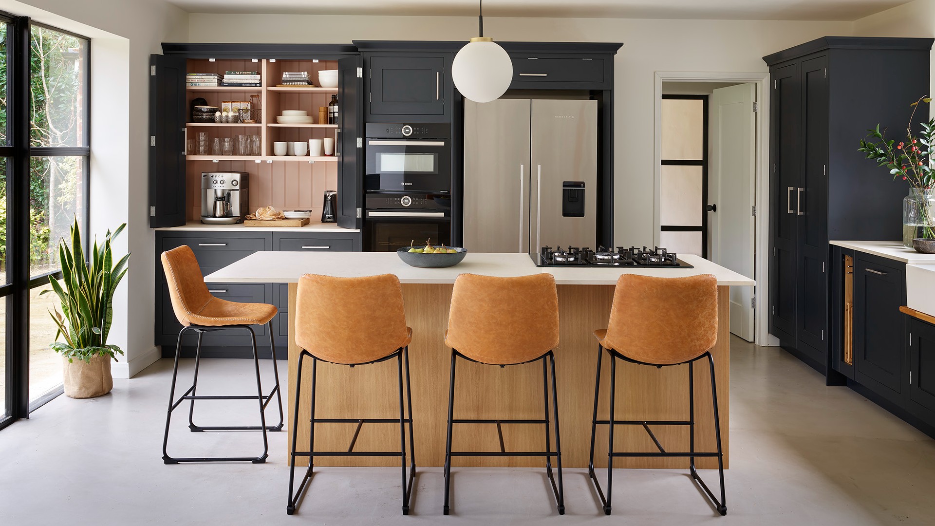 a modern kitchen with a white island blue cabinets an open coffee station and drinks station and doors to the left