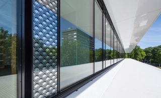 daytime, outside image of the Grotius Building, Nijmegen, view from the glazed walls divided by white canopy design features, defining each floor level, surrounding trees, blue sky