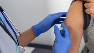 Close-up of a person getting a vaccine in their upper right arm. 