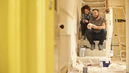 Couple choosing paint while sitting on the stairs in a home they are decorating