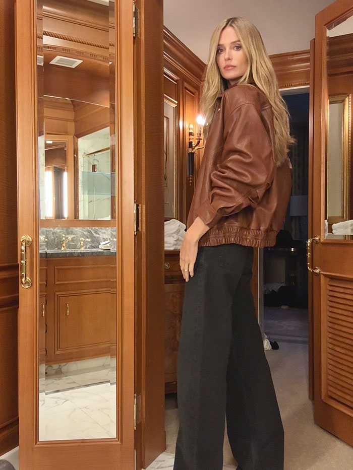 Kate Love wearing a brown leather jacket and black jeans.