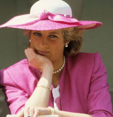 Princess Diana wearing a pink blazer and white hat resting her chin on her hand at the 1987 Epsom Derby 