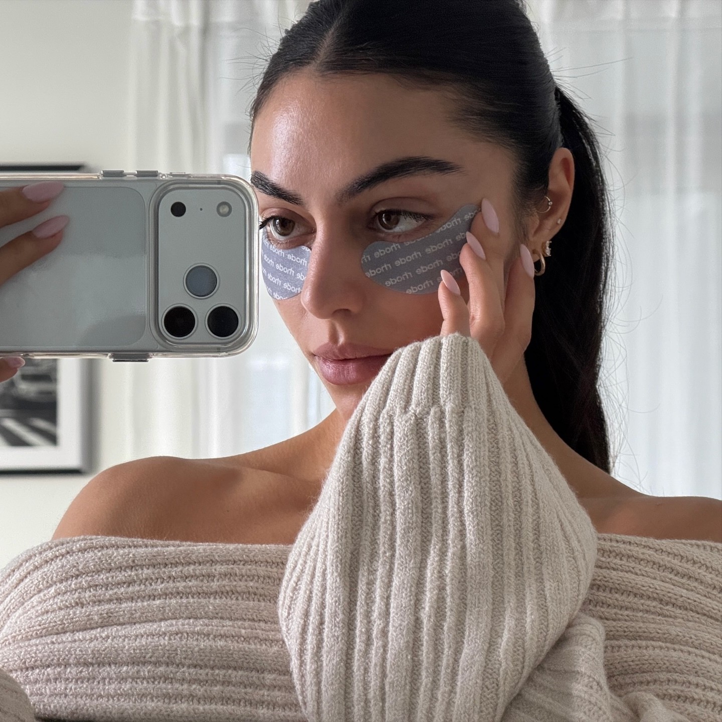 Photo of a woman wearing eye patches taking a mirror selfie
