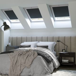 King size bed underneath trio of skylight windows with blackout blinds