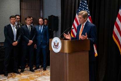 John Kerry speaks at a lectern in front of U.S. flags 