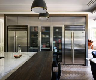 bank of floor to ceiling stainless steel built in appliances on kitchen wall