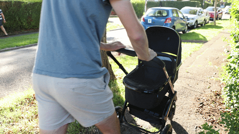 A tall man pushing the Ickle Bubba Stomp Luxe Elements pram