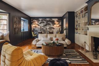 A dark blue living room with a dining table at the back and sofa and yellow chair arranged in front around a coffee table