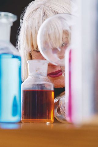 woman peeking through various colour bottles