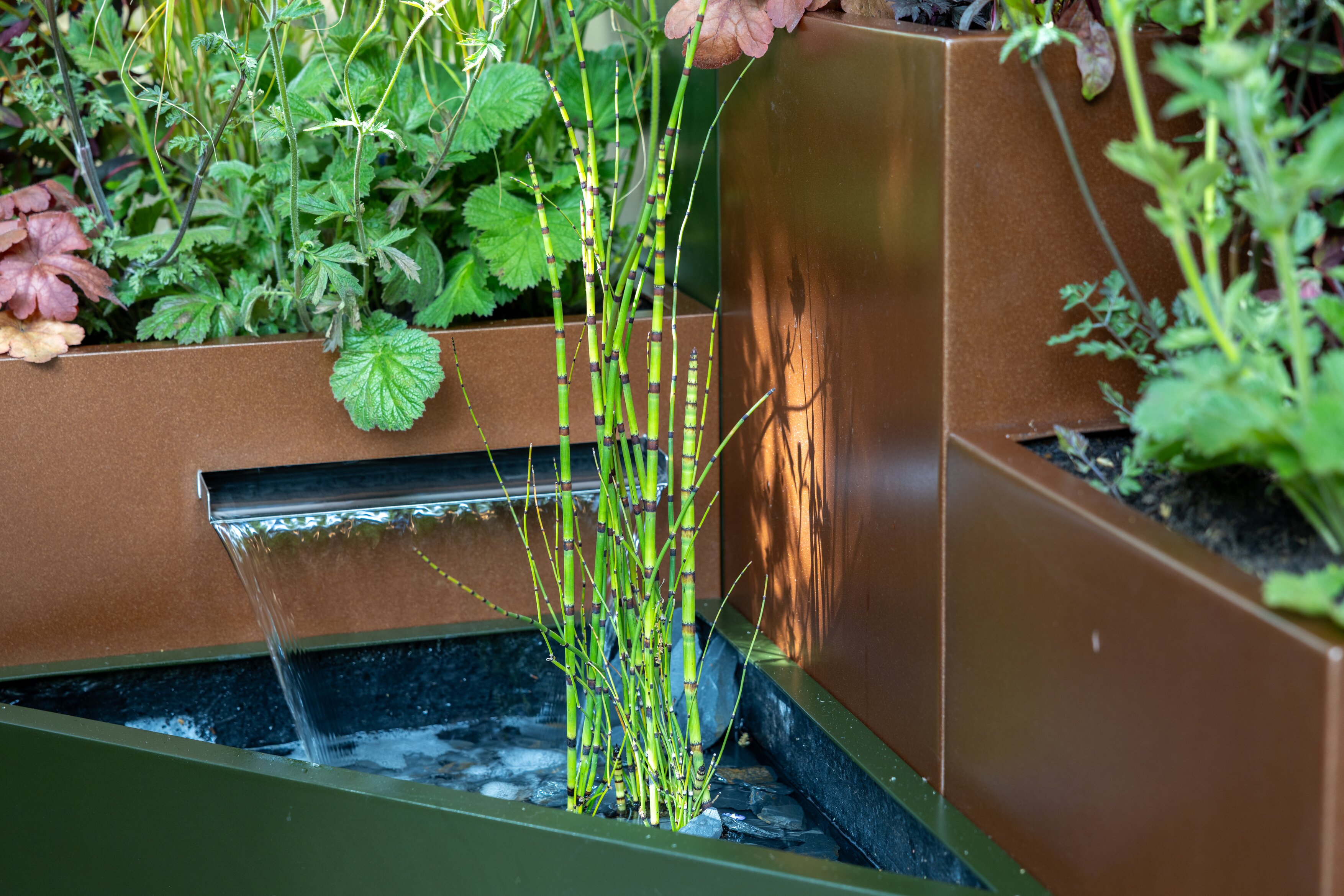 Images and details showing the planting and structure of the transient garden. Lots of brick, leafy greens and brushed metal