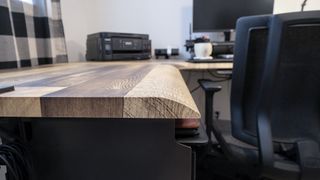 A closeup shot of the reclaimed wood laminate desktop on the Vari L-Shape Electric Standing Desk