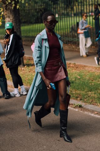 woman wearing blue trench coat, burgundy dress, and black knee-high boots