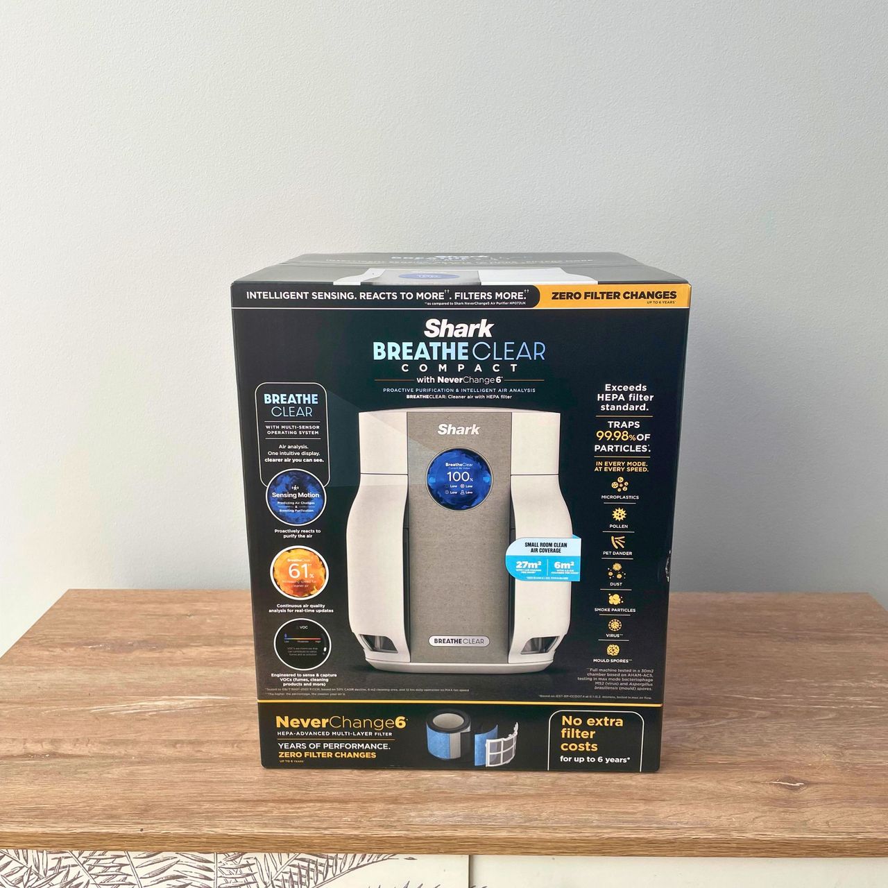 Shark BreatheClear Compact Air Purifier with NeverChange6 box sitting on wooden cabinet in front of a grey wall
