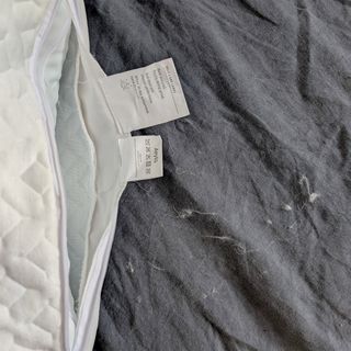 The Aeyla Adjustable FOAMO Pillow being tested on a bed with a grey linen duvet cover