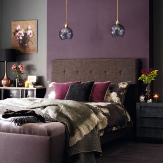 Purple bedroom, double bed with large brown headboard, pendants, dark bedside tables.