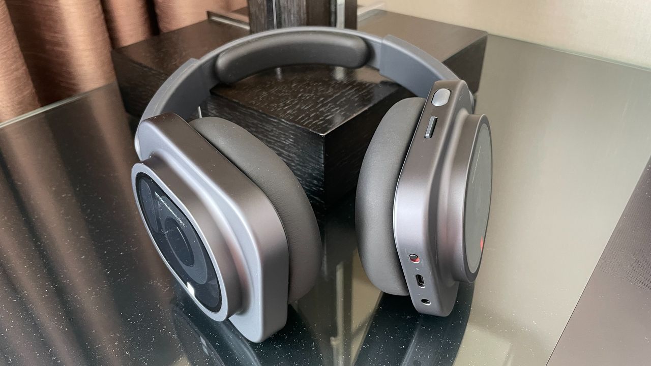 Nothing Headphone (1) Pro with the case on a shiny black and glass table, held in a hand