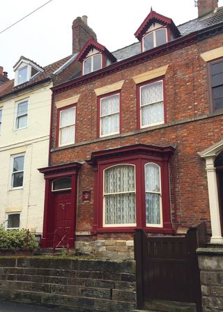 A Victorian terraced home with the typical bay window and painted in original colours