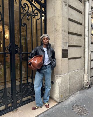 Marilyn Nwawulor-Kazemaks wearing a black leather jacket with jeans and brown Adidas SL 72 sneakers.