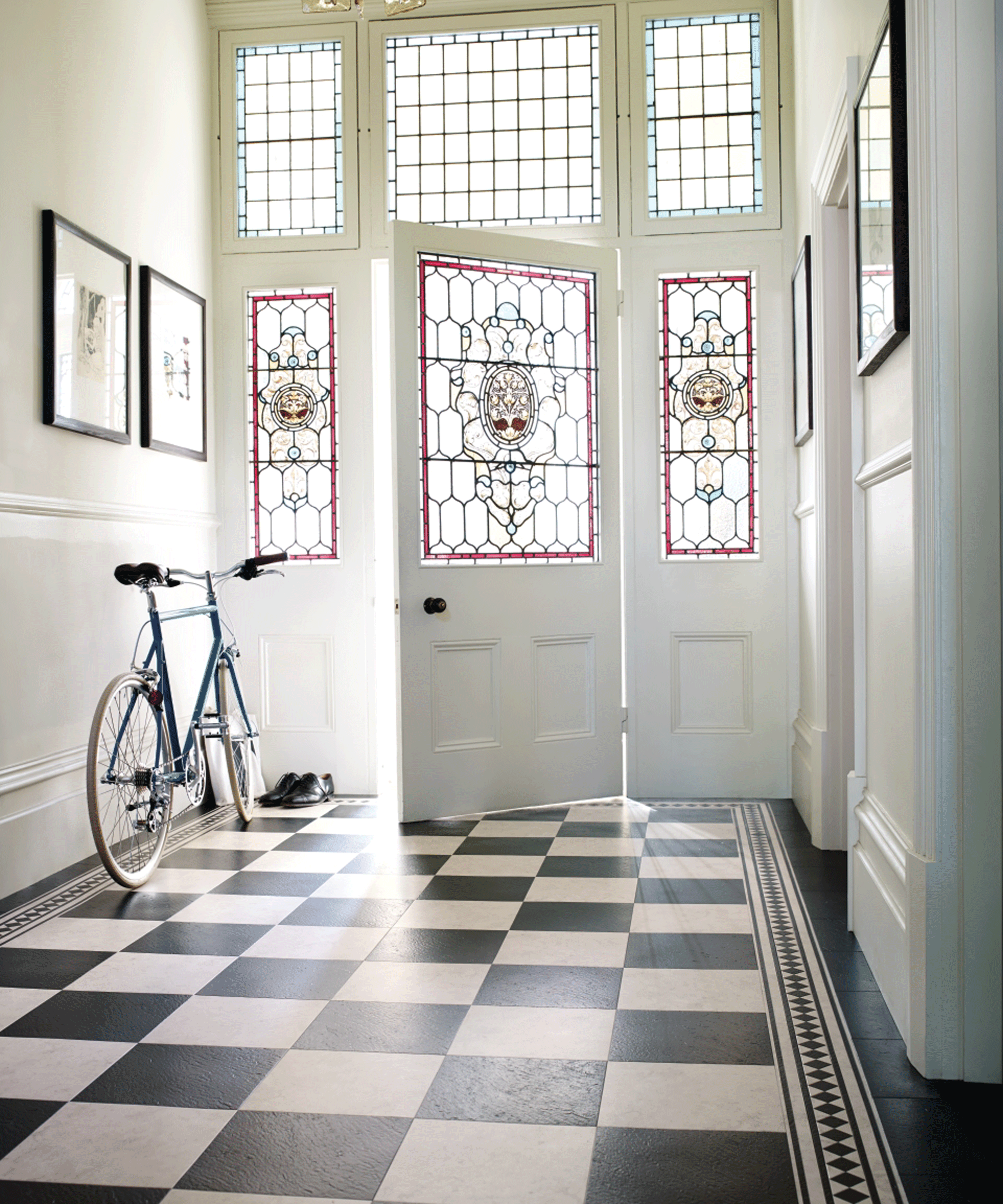 White hallway with stained glass front door and chequerboard vinyl flooring