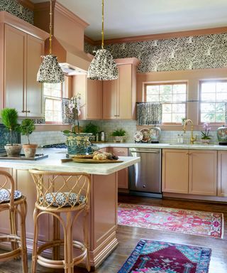 Pale pink vintage style kitchen with vintage rugs and bar stools