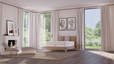 Saatva bedroom with white walls, wooden flooring, large windows with white curtains, and white fireplace.