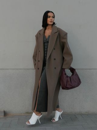 woman wearing white mules with long coat, long maxi skirt, and waistcoat