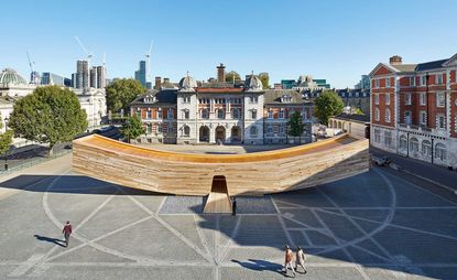A timber structure in the middle of a square in Central London. The structure is shaped like a smile. 