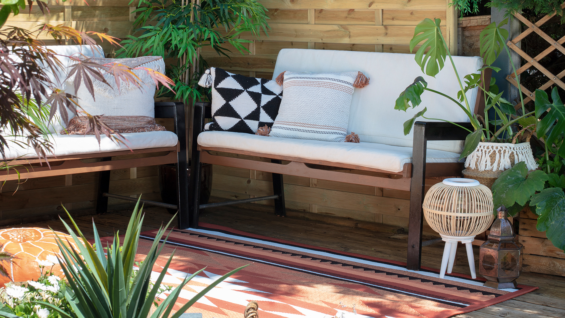 Shaded corner of a garden with bench seating with cushions and a rug