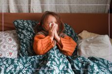 Child laying in bed and blowing her nose