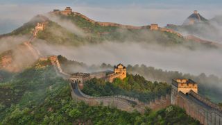 Fog along the Great Wall of China snaking along the mountainous landscape.
