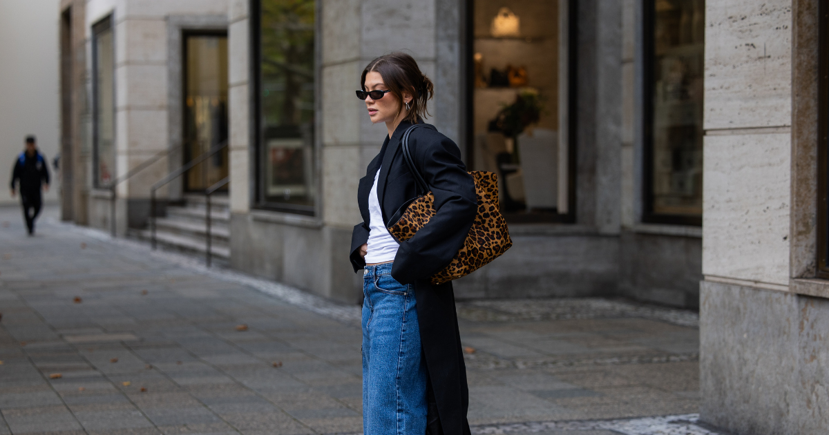 Boots beauty Sophia Geiss wears animal print Demellier bag, oversized black coat, white shirt, denim jeans on October 13, 2025 in Berlin, Germany.