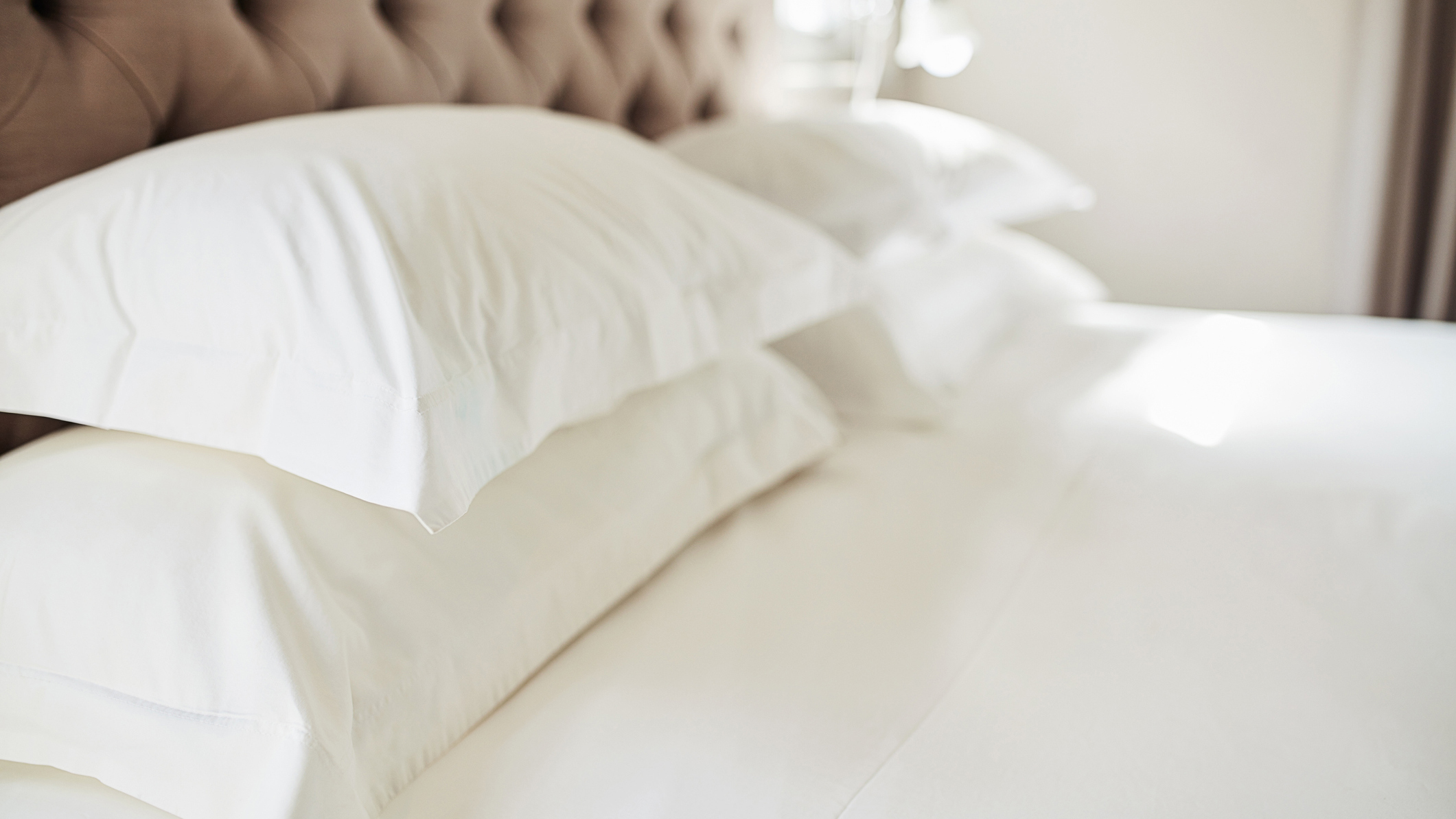 Image shows four white pillows placed on a white mattress
