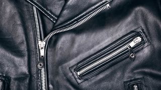 A close up of a black leather jacket with zips