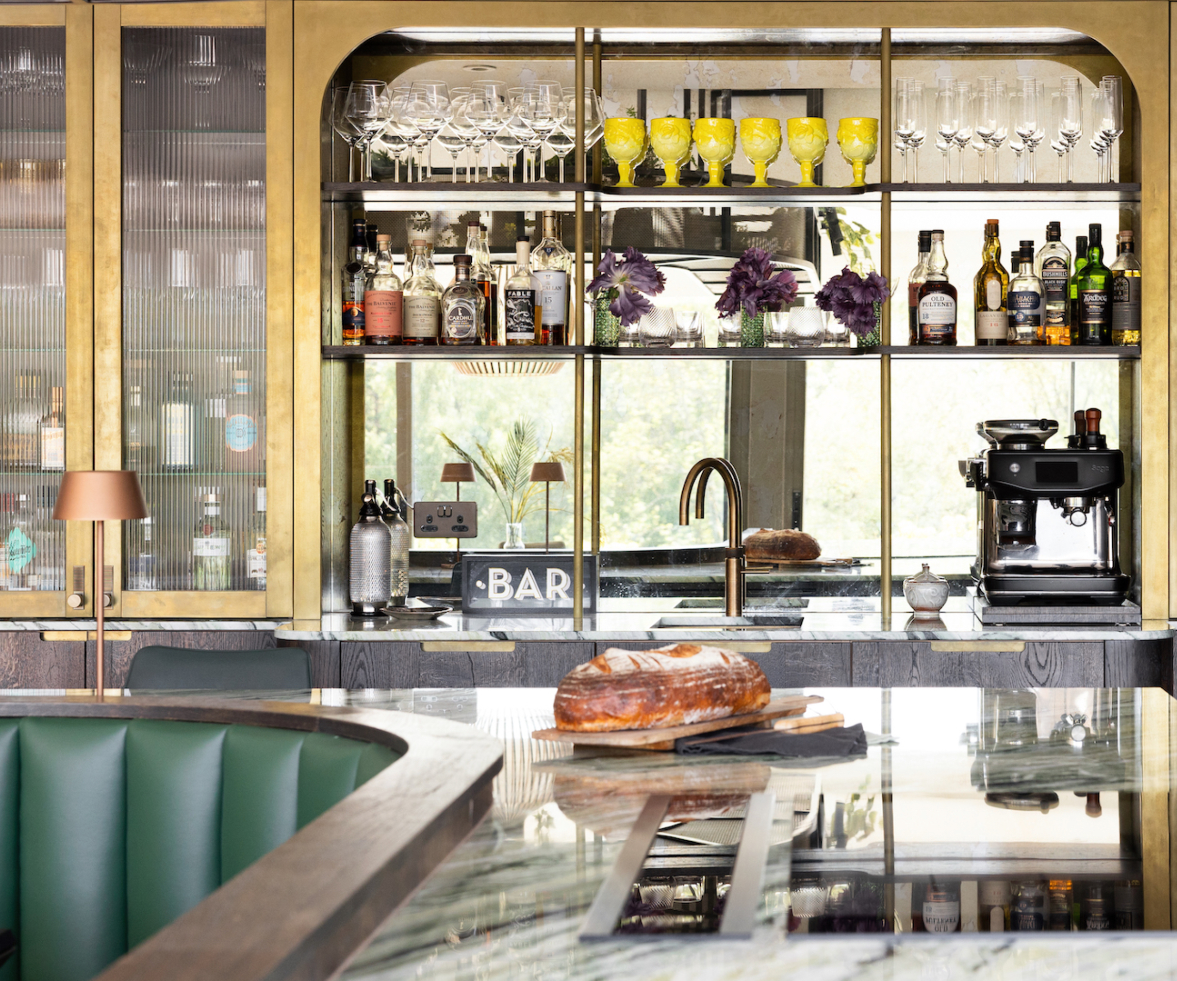 Art Deco style kitchen bar with gold wall cabinets and green banquette