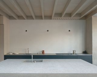 Kitchen with concrete island at Concrete Plinth House by DGN studio