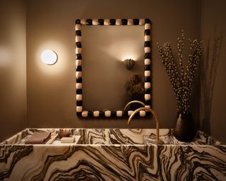 a white and black marble vanity with a black and white bobbin mirror