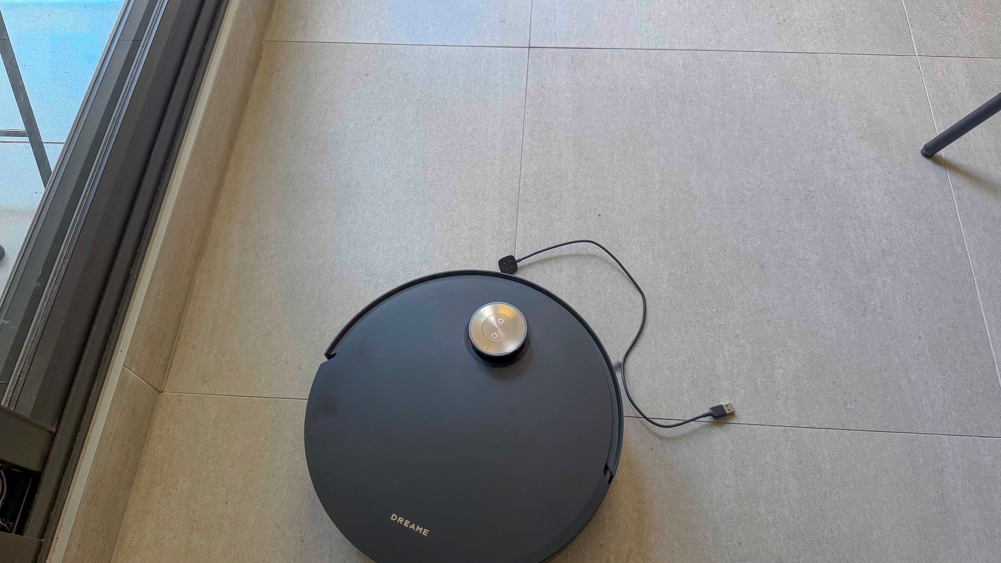 Dreame Aqua10 Ultra cleaning alongside a charging cable on the floor